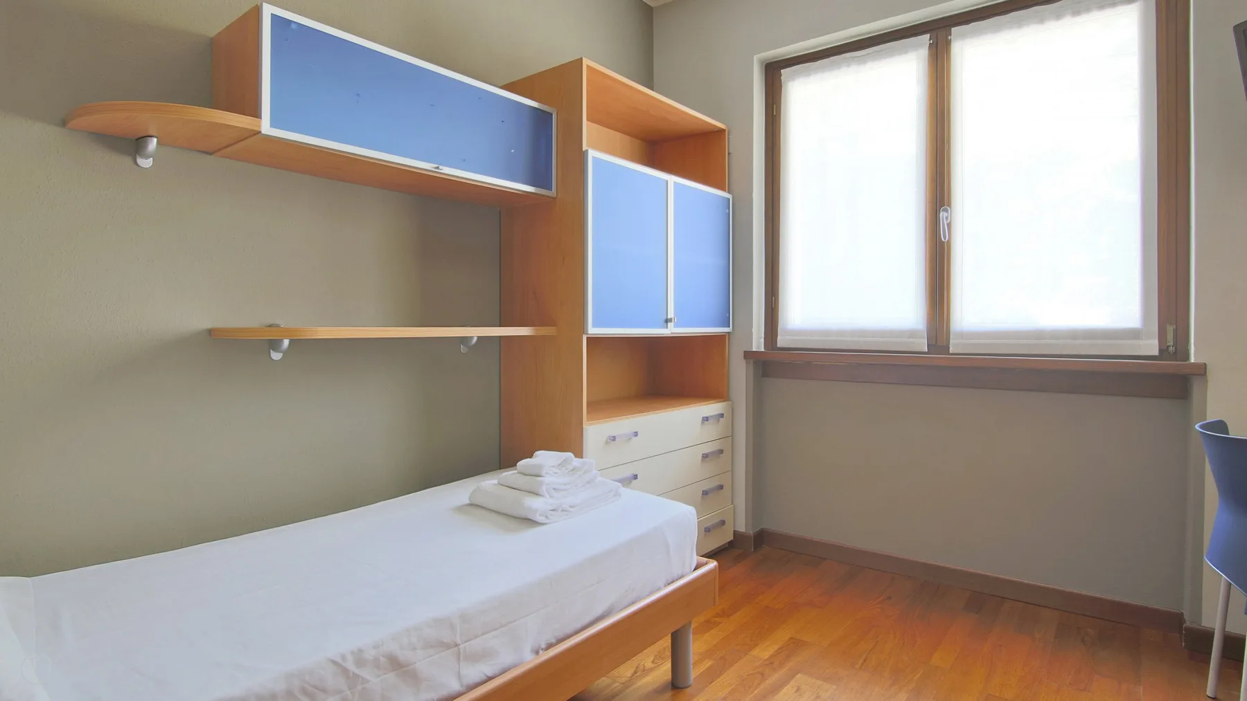 A treatment room with a padded table, storage cabinets, and a large window.