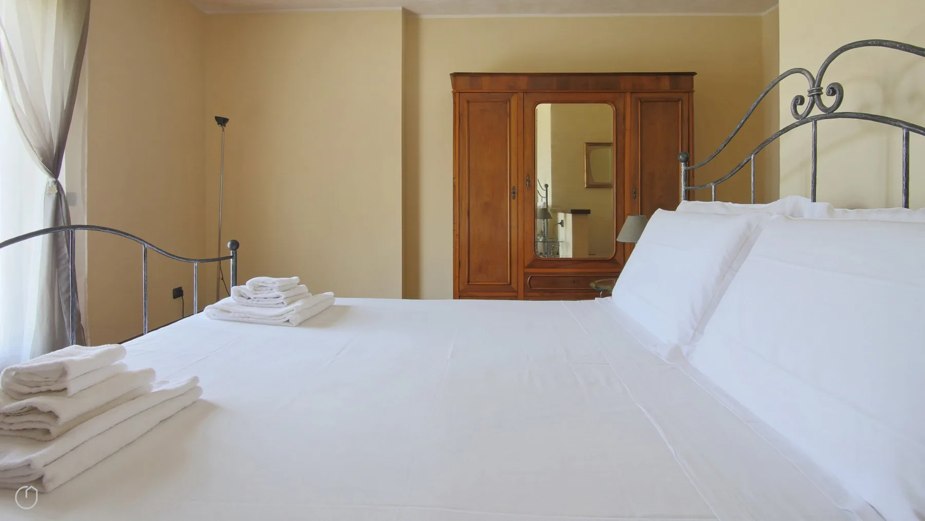 A bedroom with a neatly made bed and folded towels.