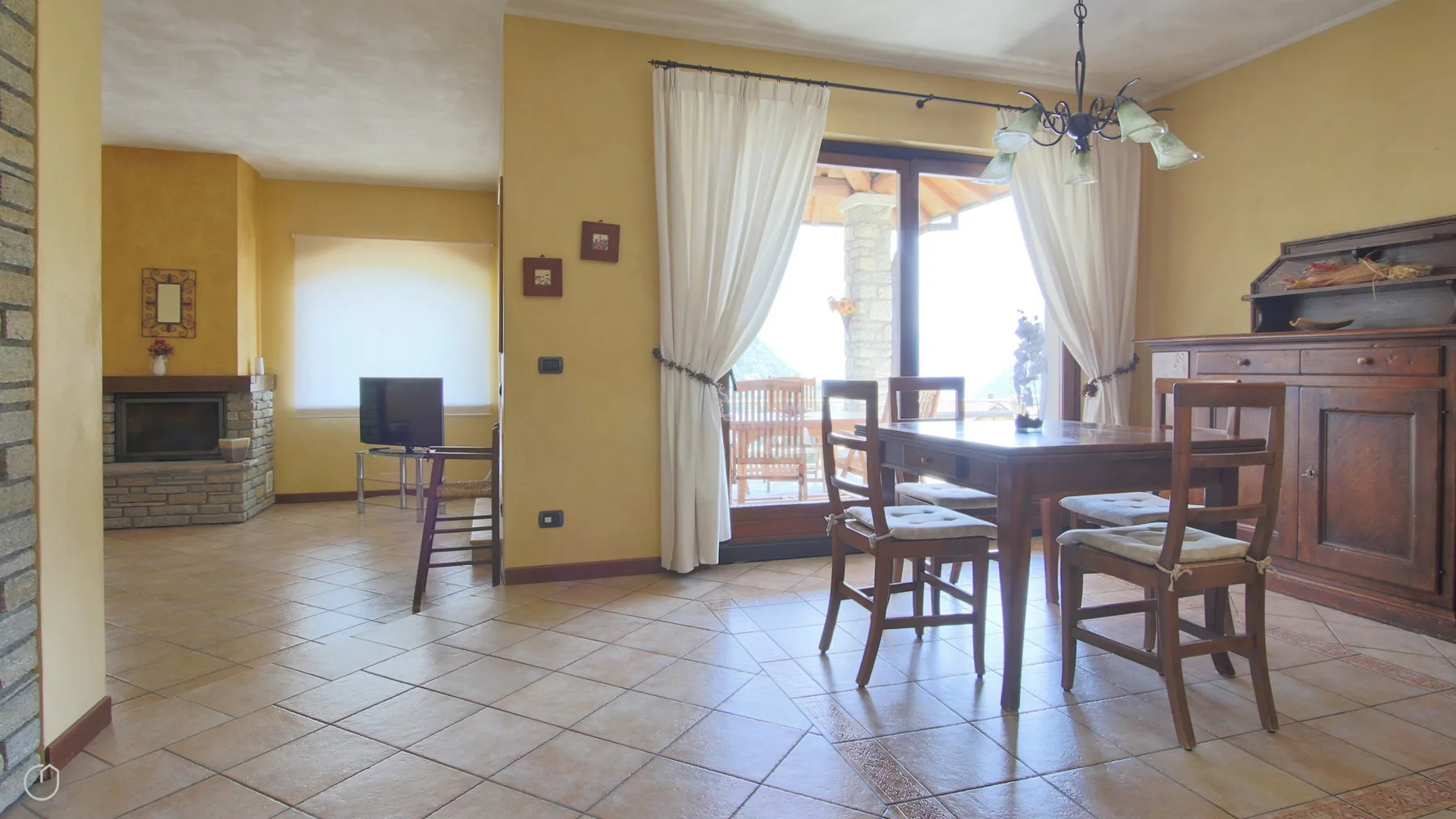A dining area with a wooden table and chairs beside curtained windows.