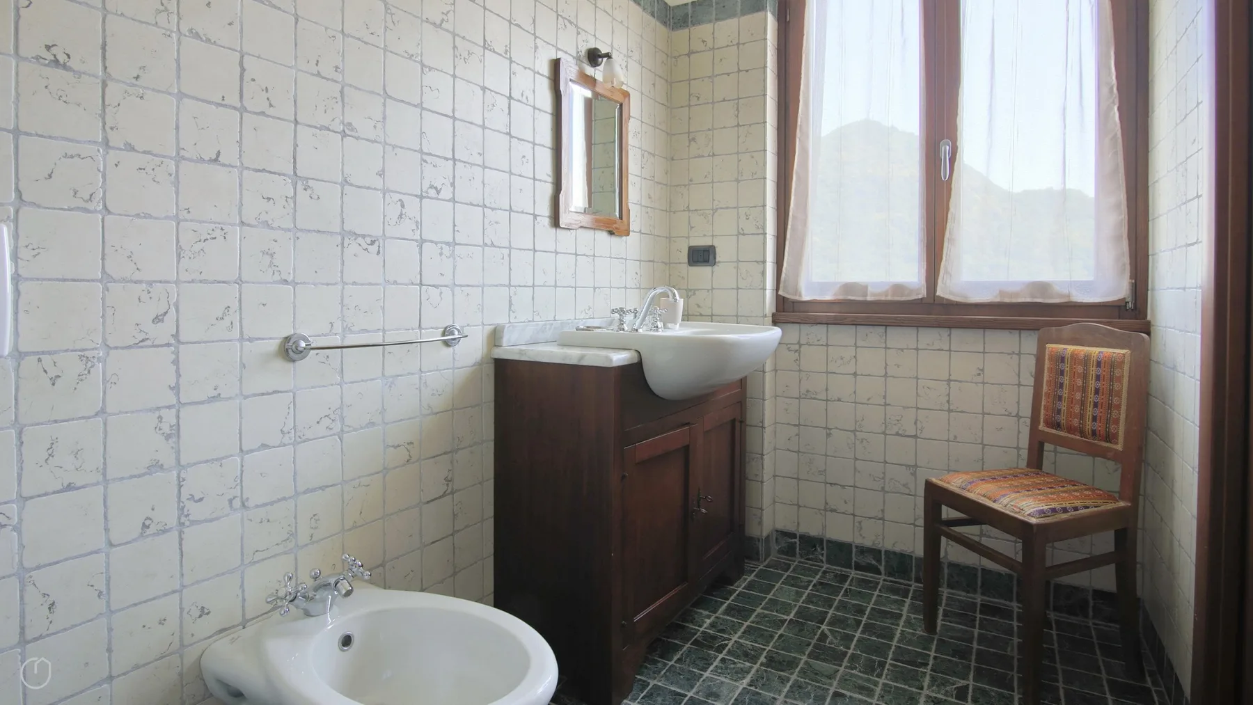 A tiled bathroom with a sink and a large window.