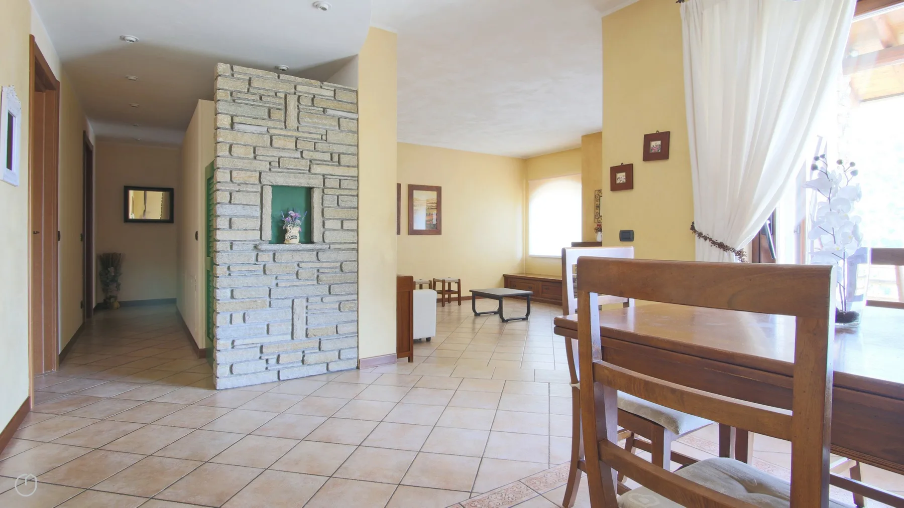 A tiled dining area opens onto a hallway, with a wooden table and chairs.