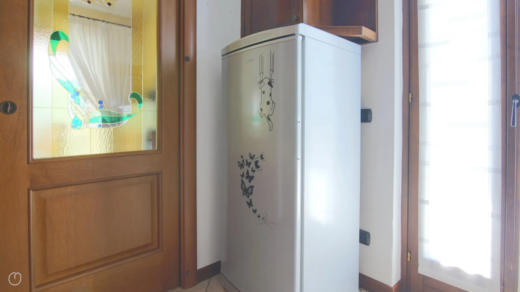A small interior area with a decorated white refrigerator beside a wooden door.