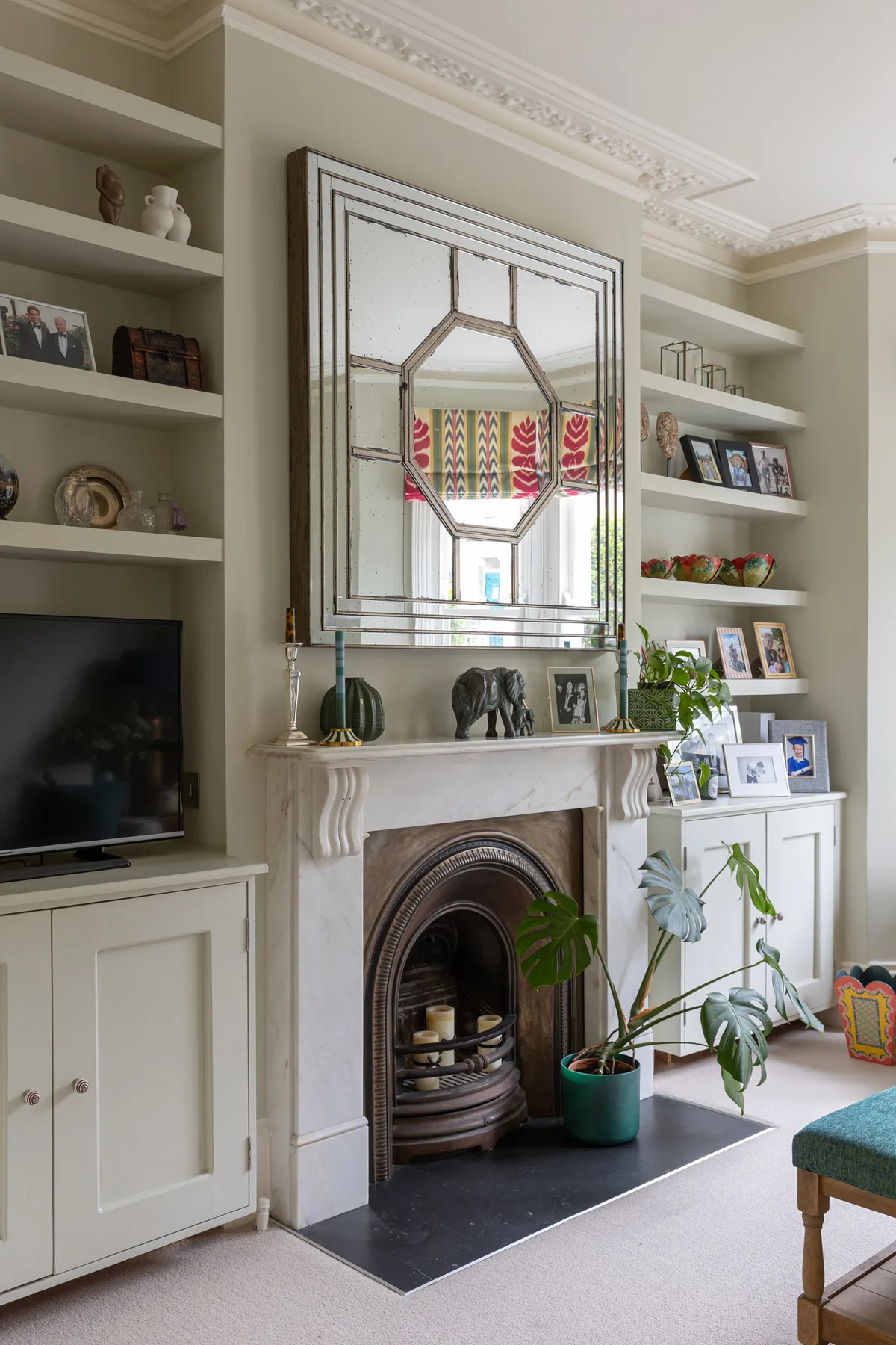 A living room with a fireplace, built-in shelves, and a large mirror.