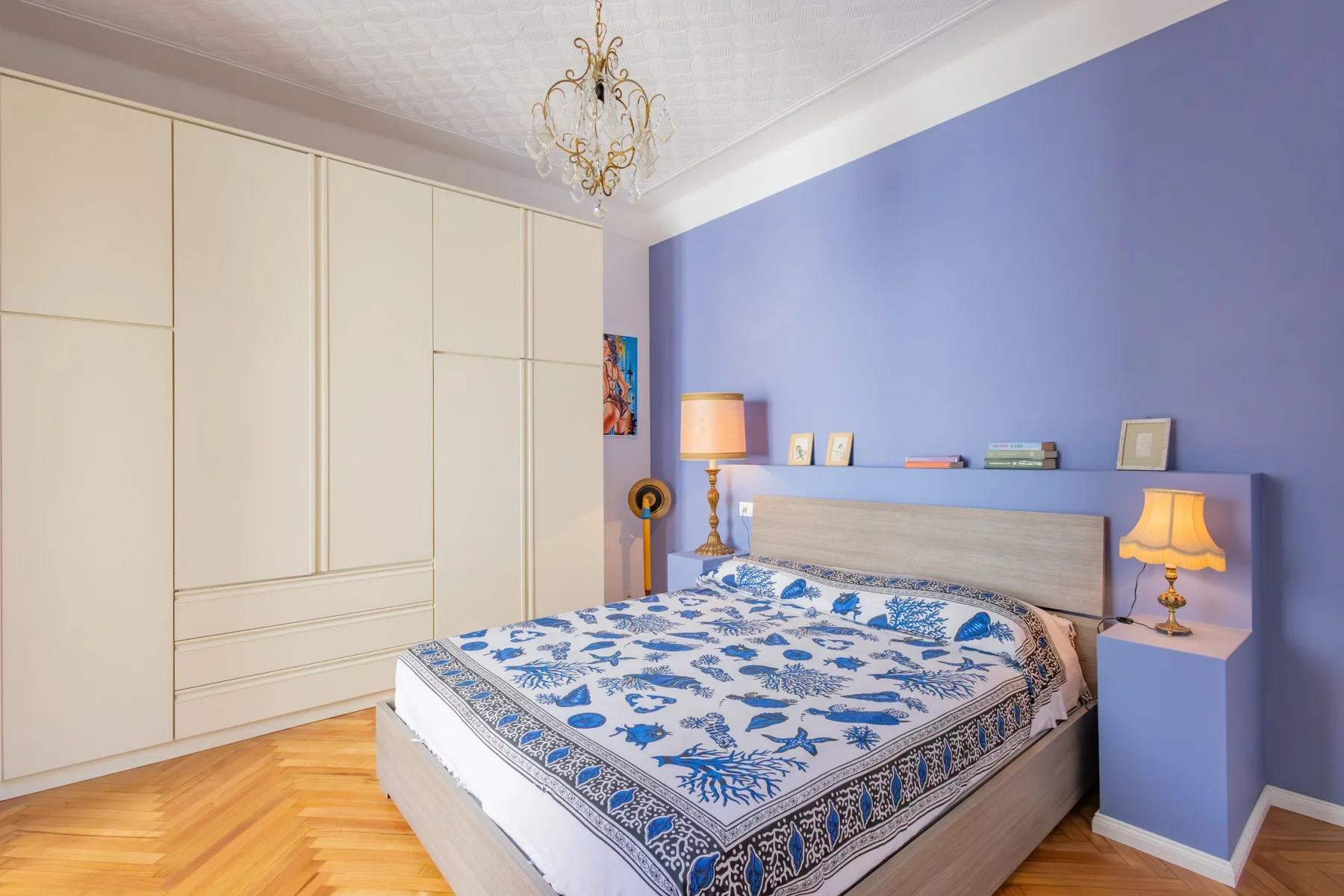 A bedroom with a blue patterned bedspread and built-in wardrobes.