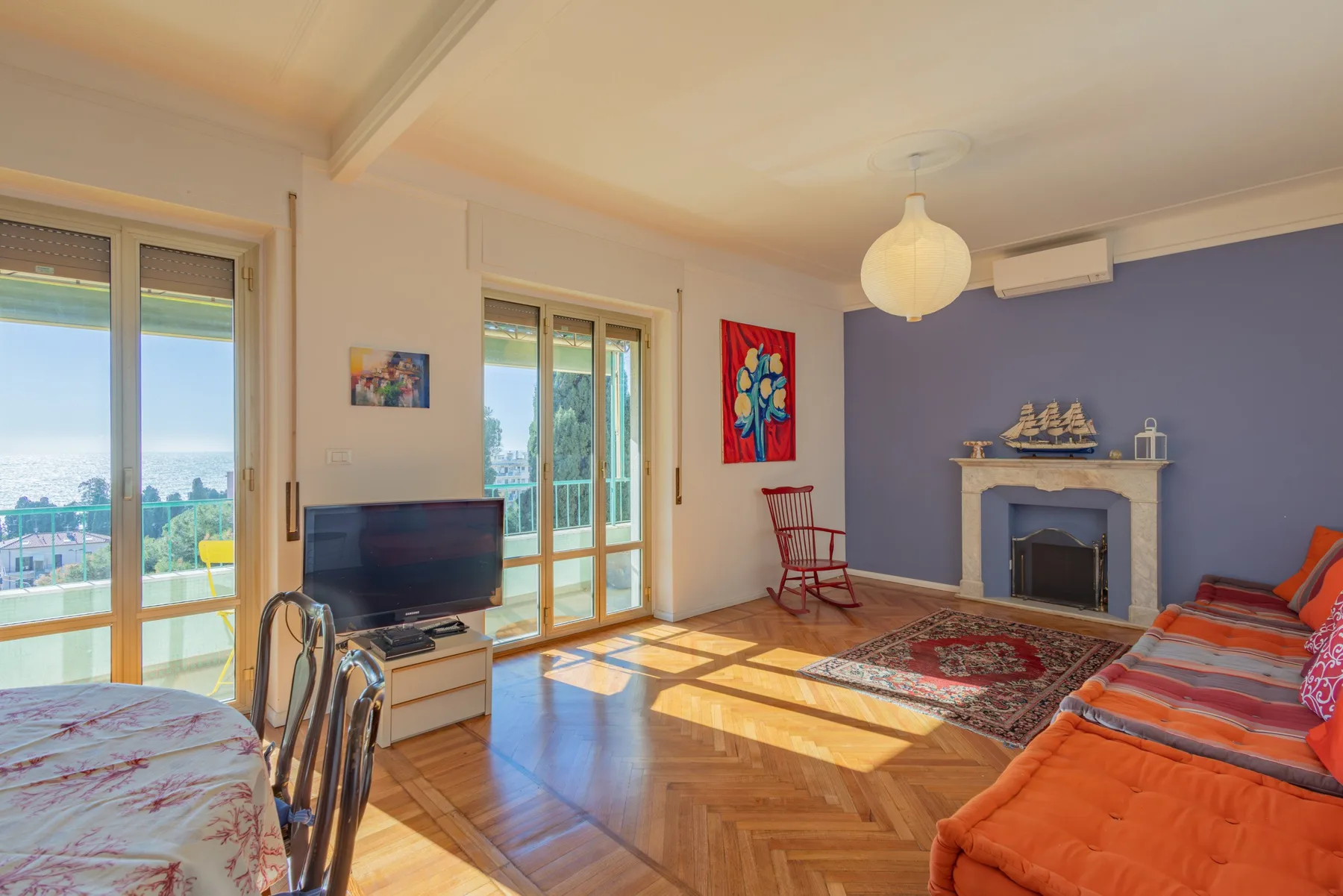 A bright living room with seating, a television, and a fireplace.