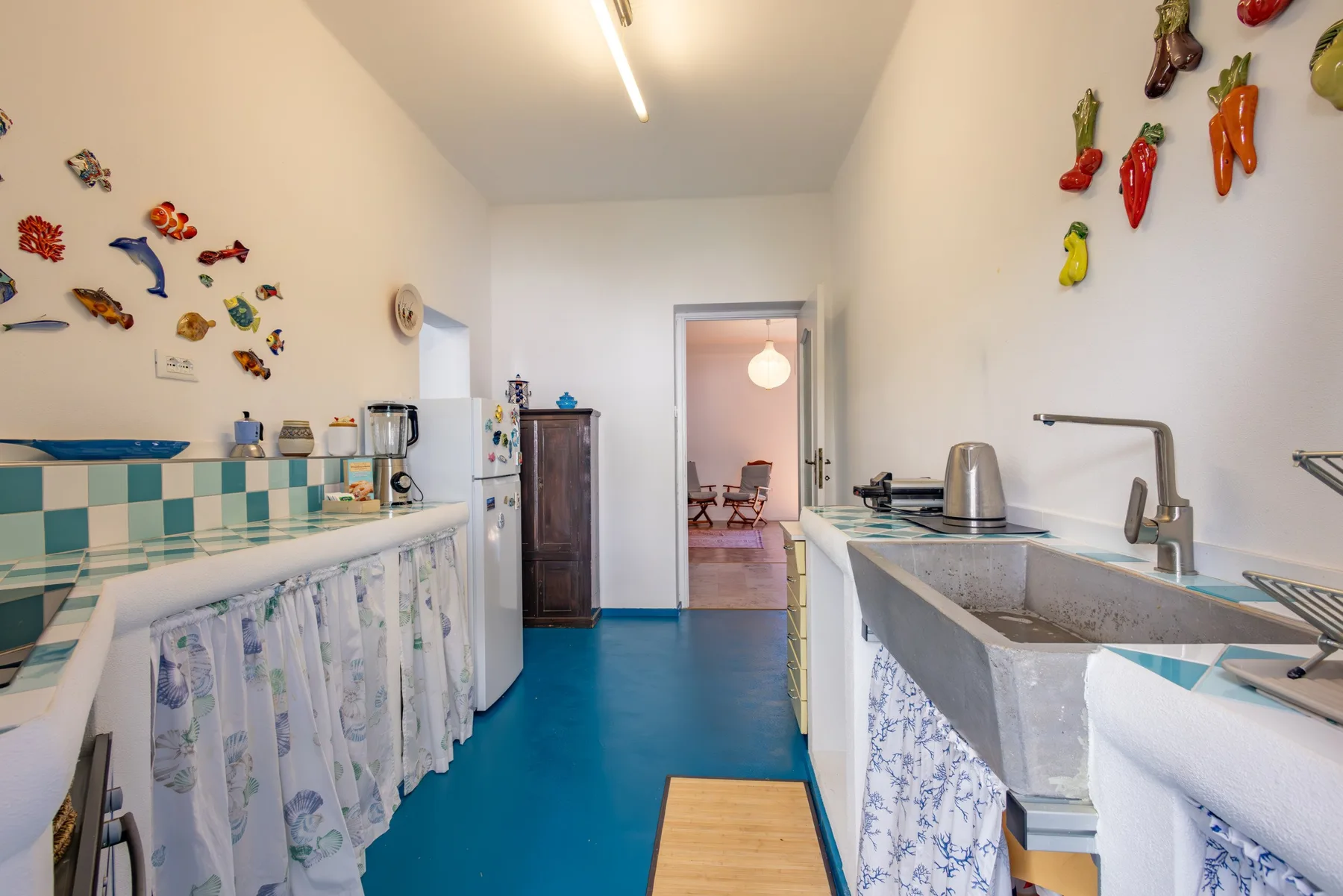 A narrow kitchen with counters on both sides and colorful decorations on the walls.