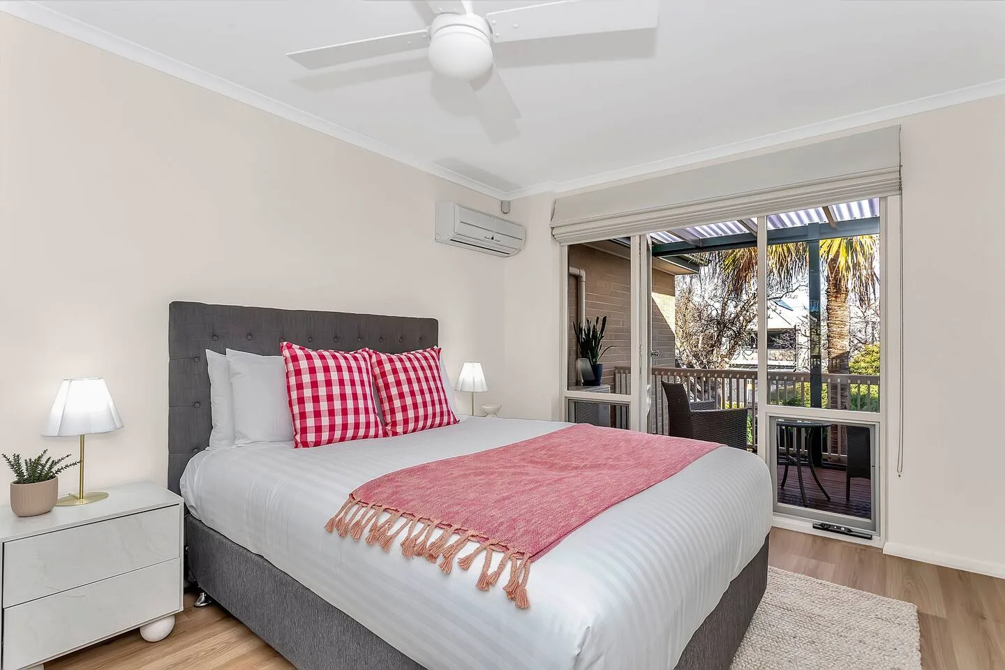 A bedroom with a neatly made bed and sliding glass doors opening onto a balcony.