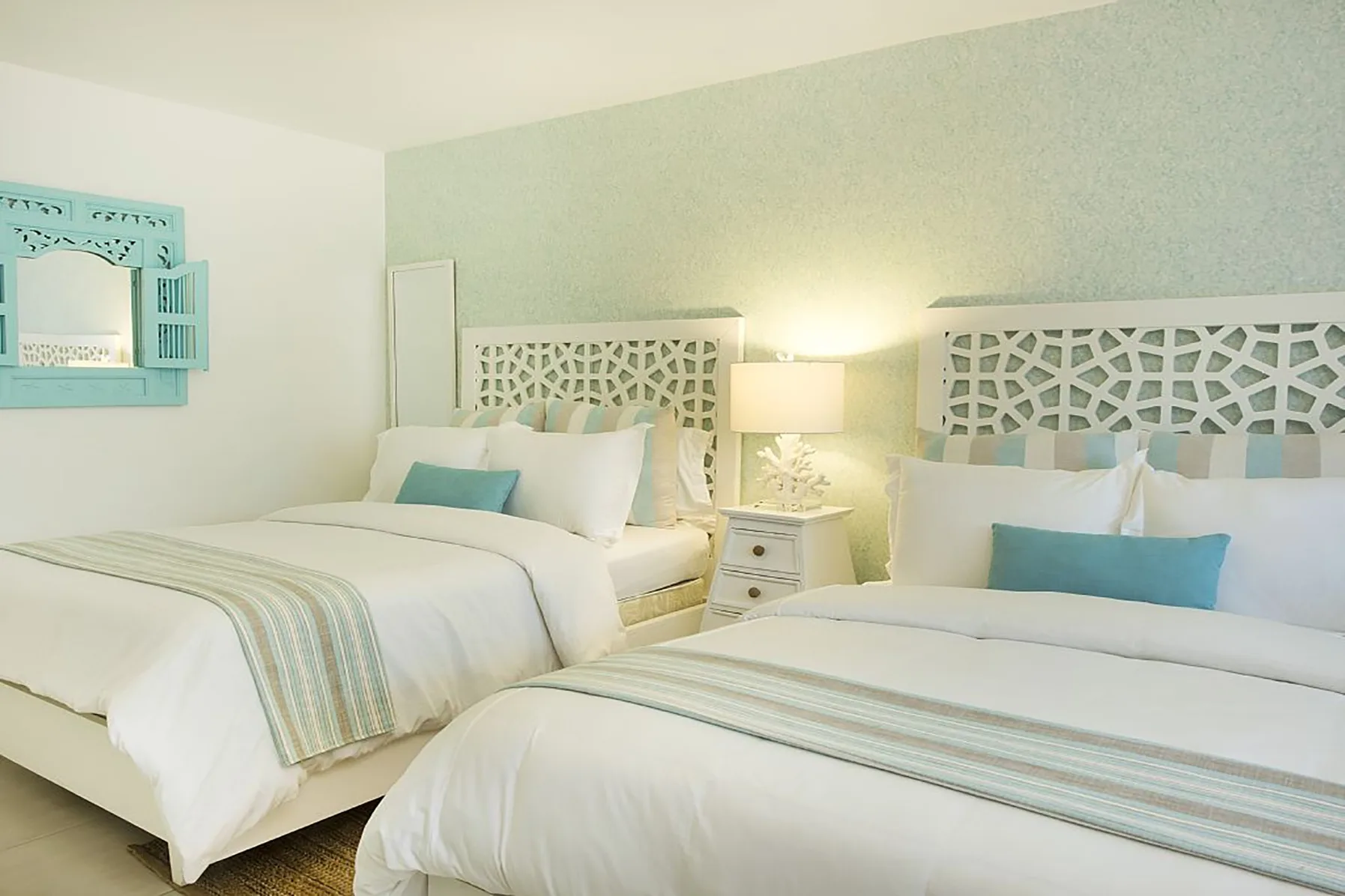 Un dormitorio con dos camas vestidas con ropa de cama blanca y cojines azules.