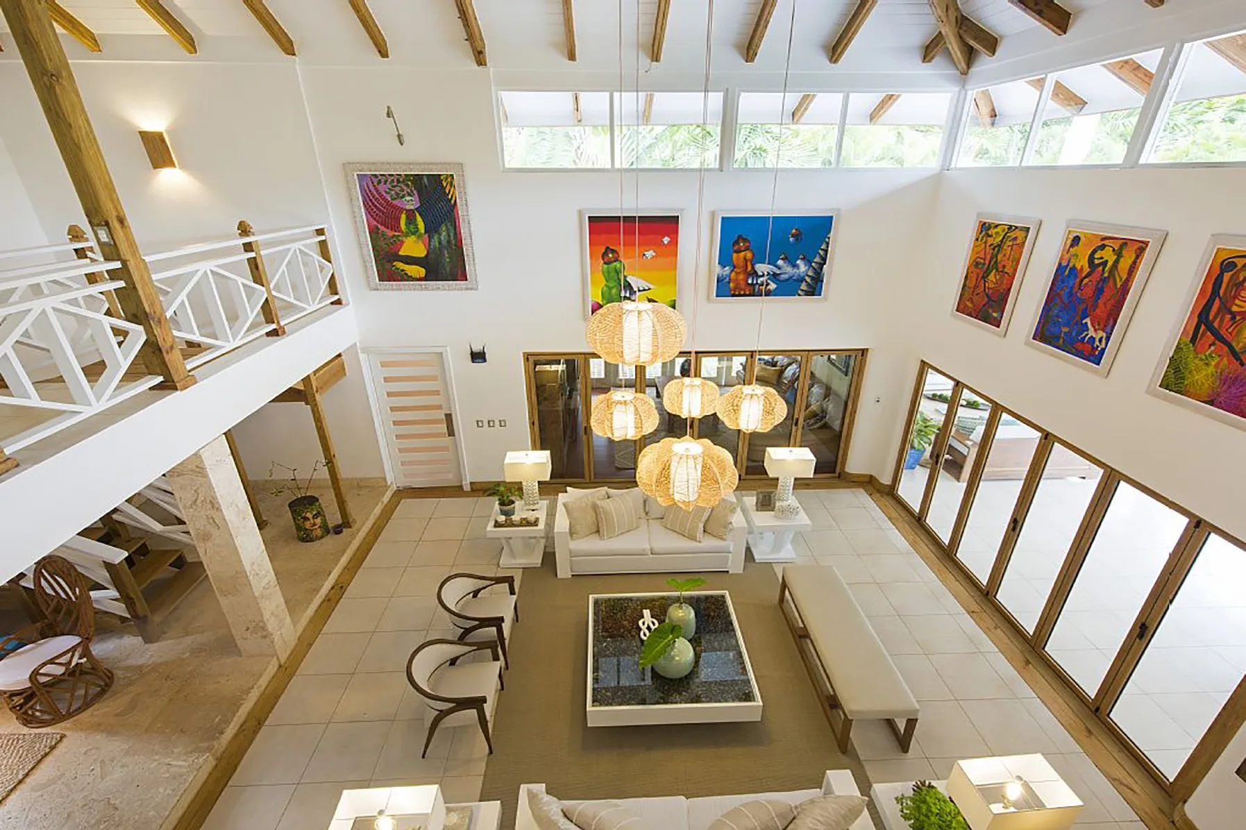 A bright double-height living room with seating beneath exposed ceiling beams.