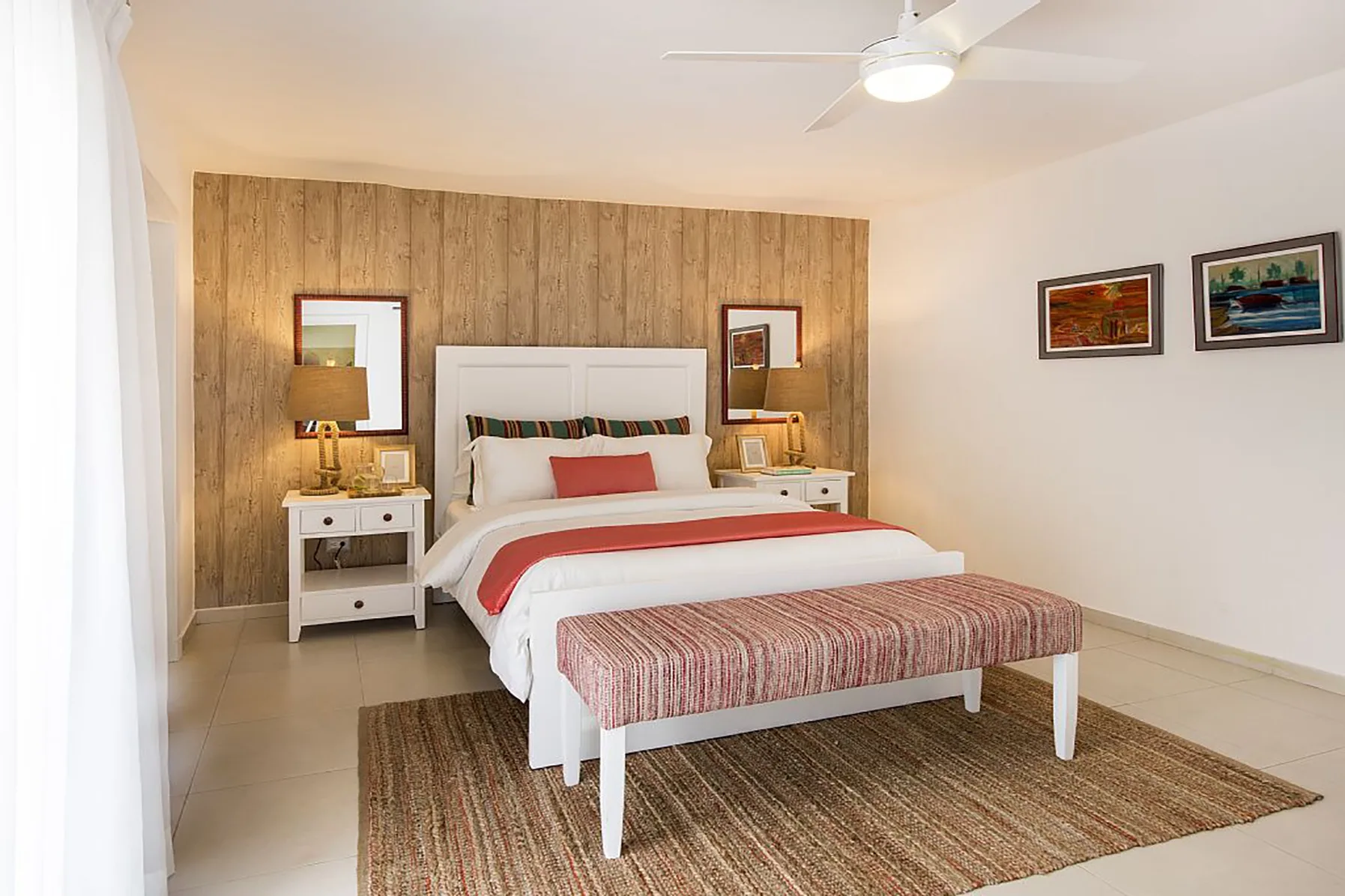 Un dormitorio luminoso con una cama, mesitas de noche y un banco estampado.