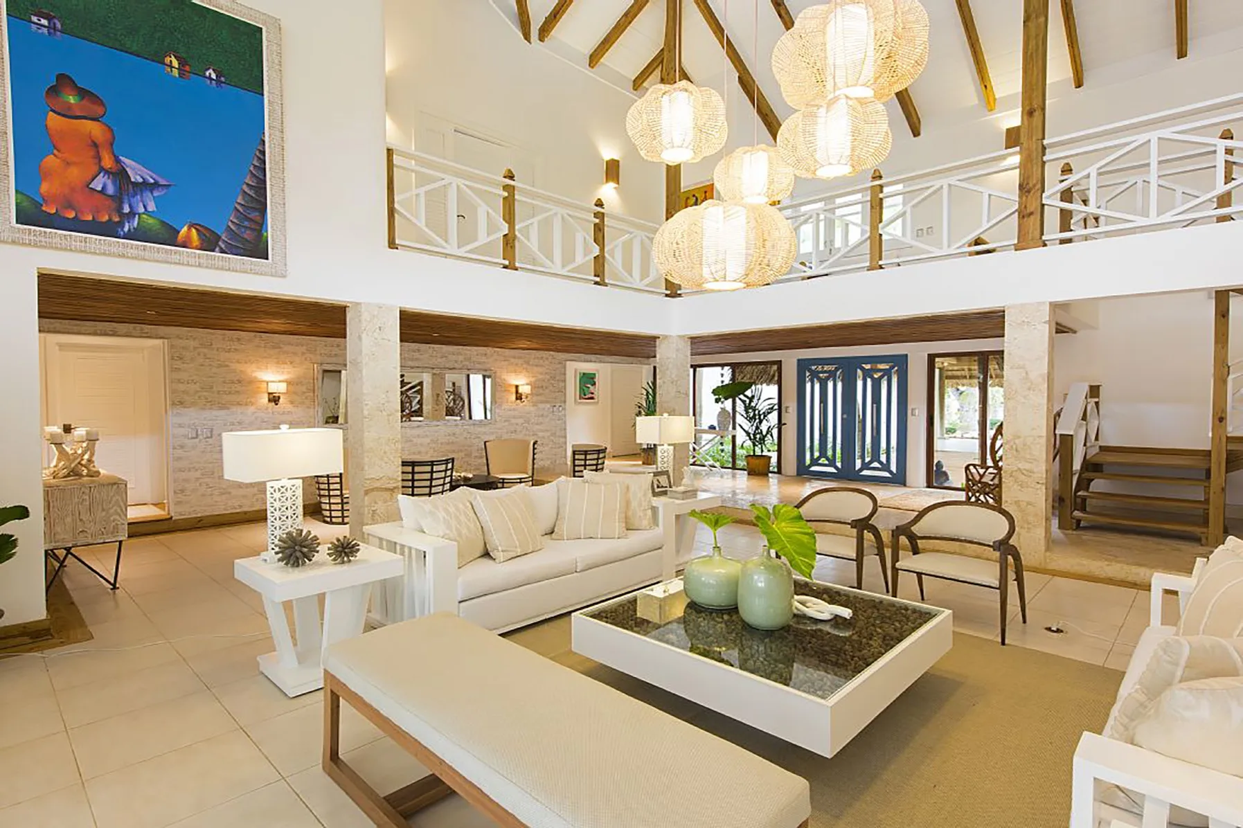 A bright open-plan living room with seating, a coffee table, and hanging pendant lights.