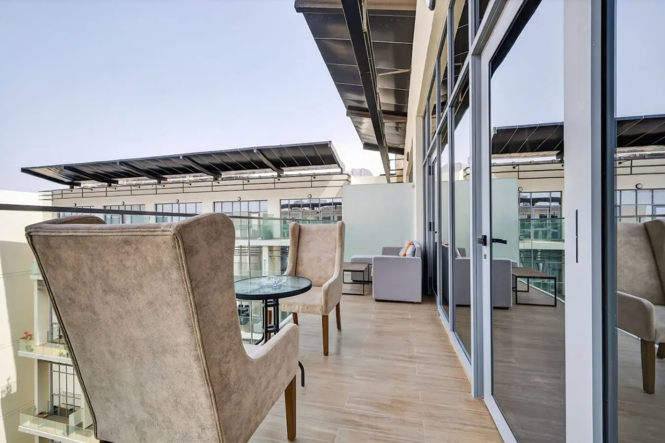 A furnished outdoor terrace with seating, a small table, and glass doors.