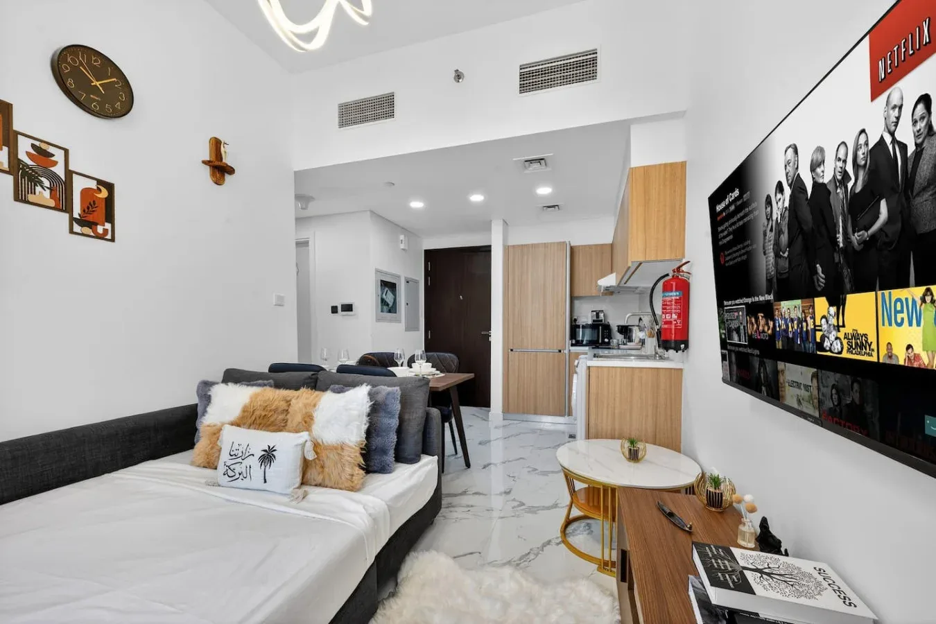 A modern living room with seating, a dining table, and a wall-mounted television.