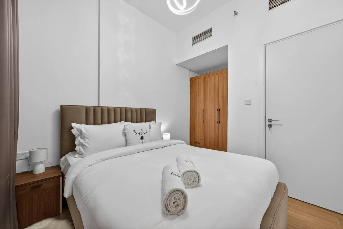 A bright bedroom with a neatly made bed and folded towels.