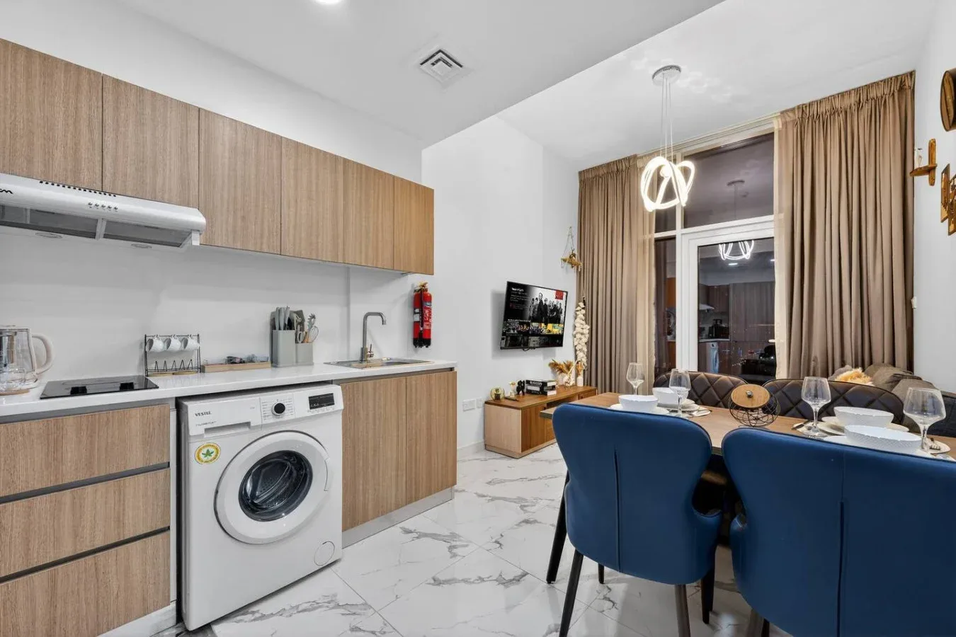 A bright open-plan kitchen and dining area with a television and blue seating.