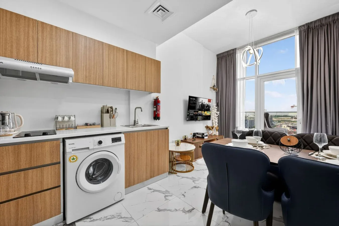 A kitchen and dining area with a washing machine and a large window.