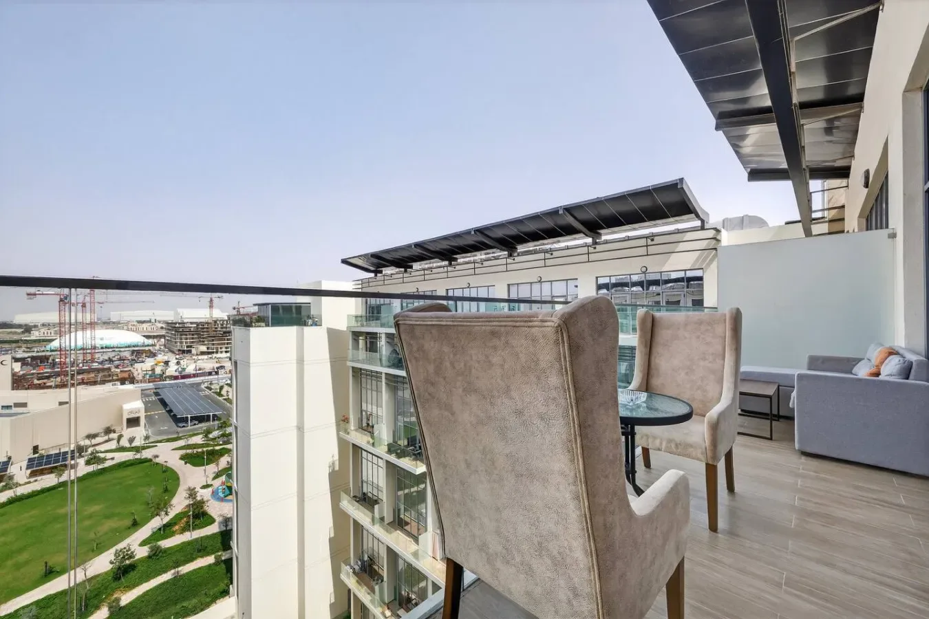A balcony seating area with chairs, a small table, and a glass railing.