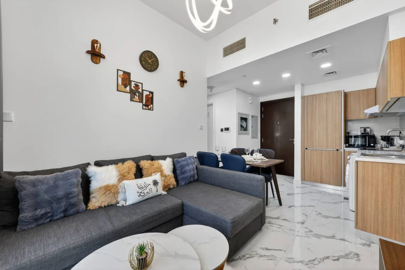 A modern living area with gray seating beside a compact kitchen.