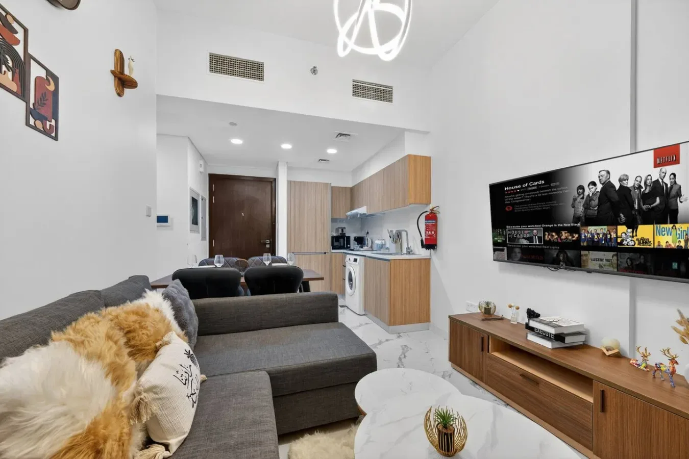 A compact living area with gray seating, a round coffee table, and an open kitchenette.