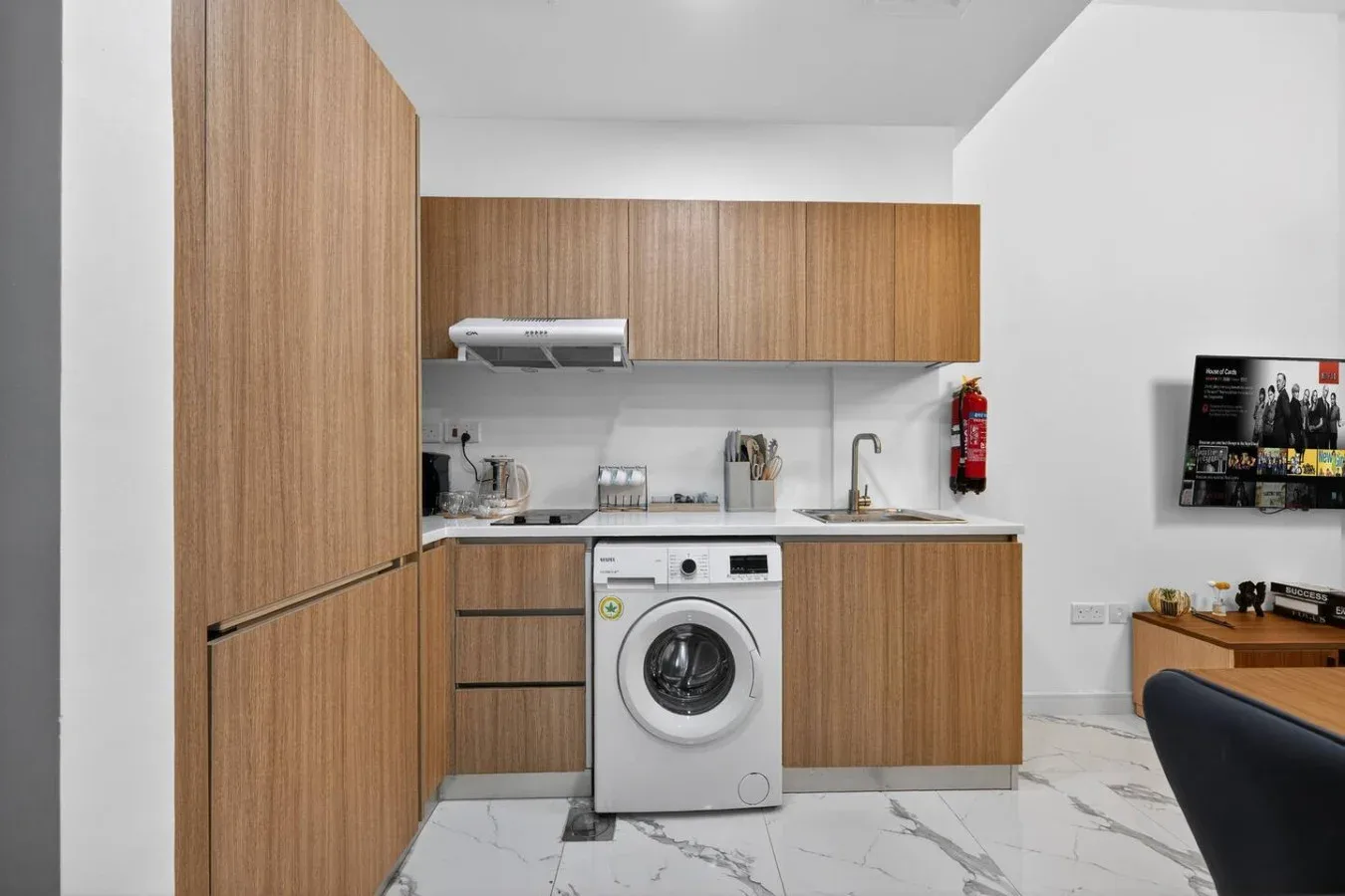 A compact kitchen with wood cabinets, a washing machine, and a countertop.