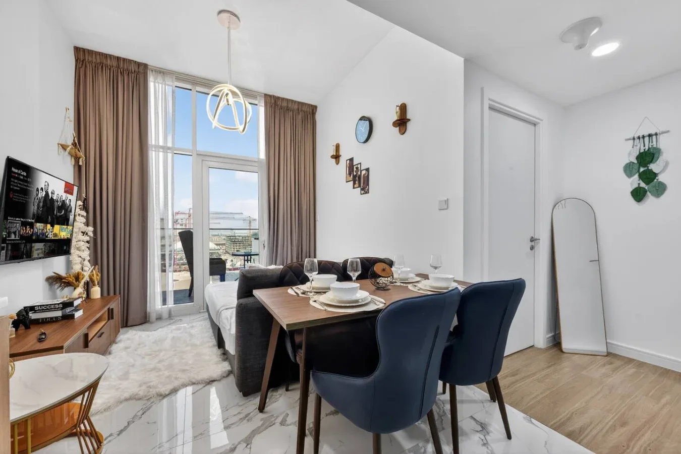 A dining area with a table set for a meal beside a bright living space.