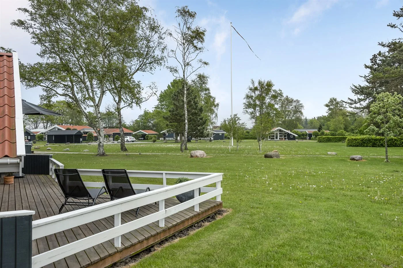 A grassy outdoor area with trees and a wooden deck.