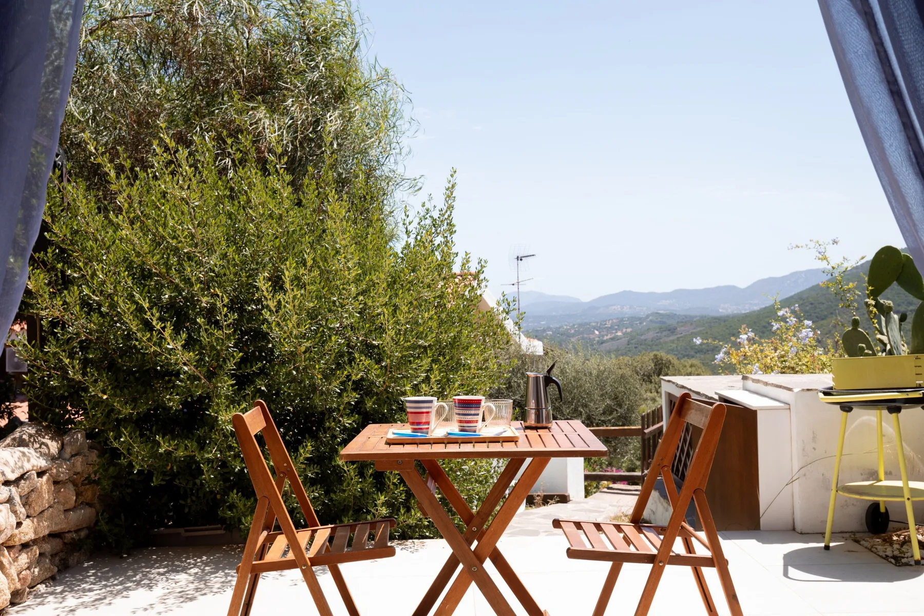 Un comedor al aire libre con una mesa de madera y vistas a las colinas.