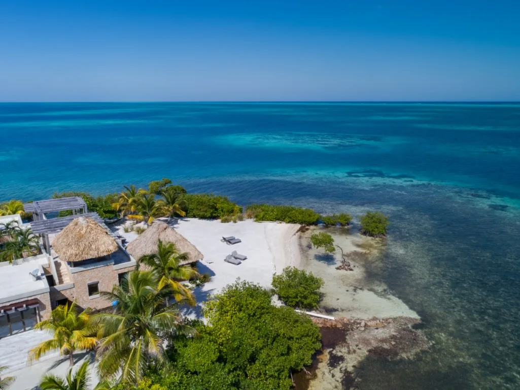 Aerial view of a tropical beachfront with turquoise water and a sandy shore.