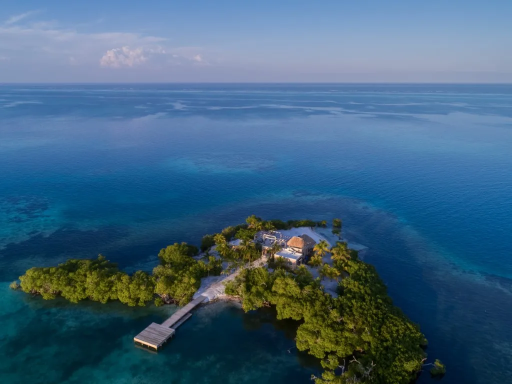 An aerial view of a small green island surrounded by blue ocean.