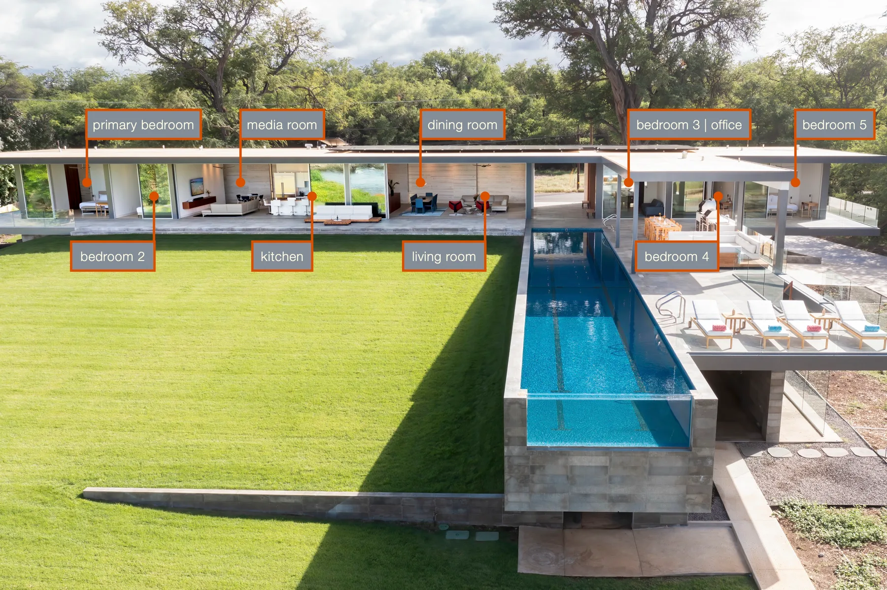 Una casa moderna se abre a una piscina larga junto a un amplio césped verde.