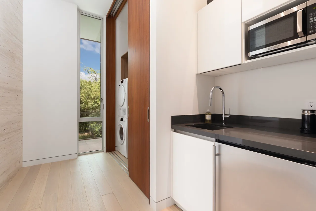 A compact kitchen with white cabinets, a dark countertop, and a sink.