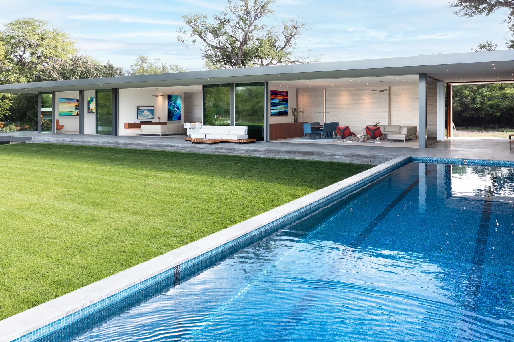 A modern house opens onto a lawn and swimming pool.