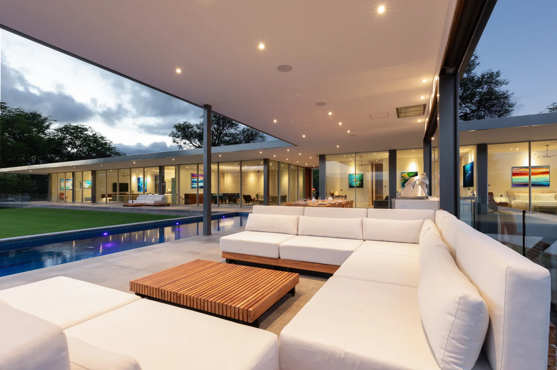 A covered outdoor seating area overlooks a pool and a modern glass-fronted building.