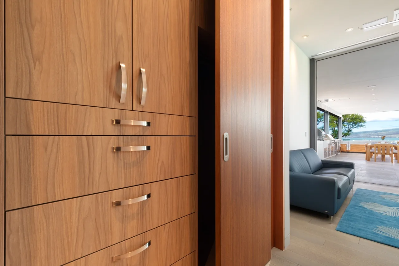 A wooden storage cabinet beside an open doorway leads to a bright living area.