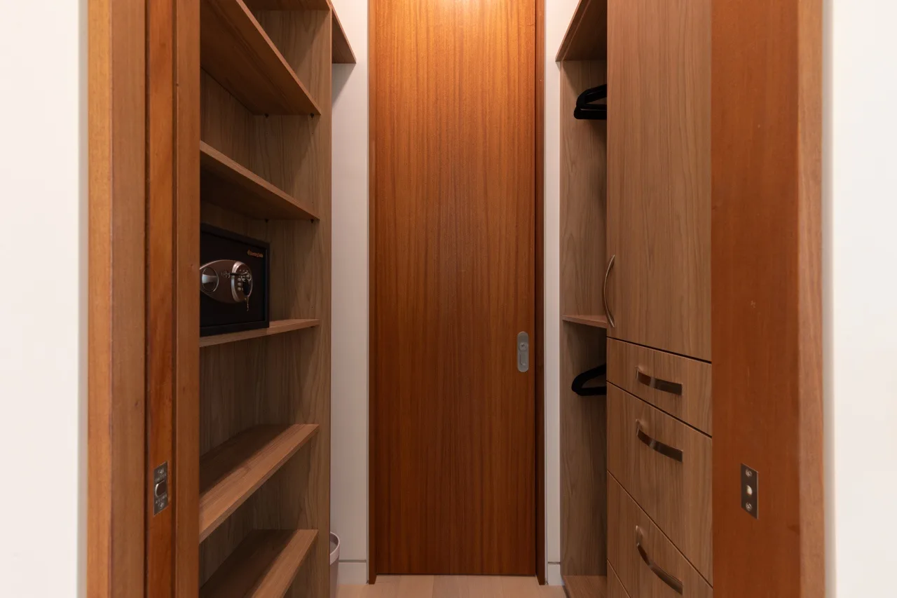 A narrow wooden wardrobe area with open shelves and drawers.