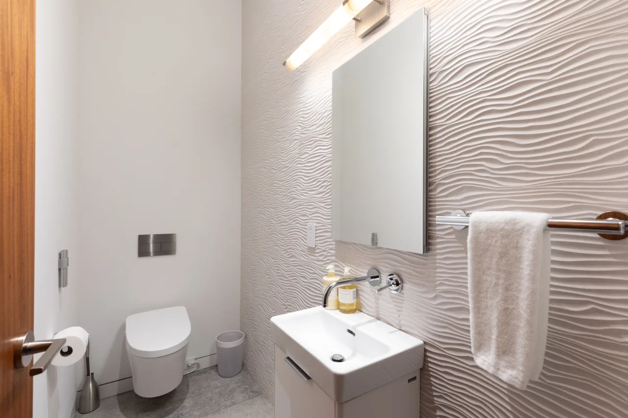 A modern bathroom with a sink, mirror, and toilet.
