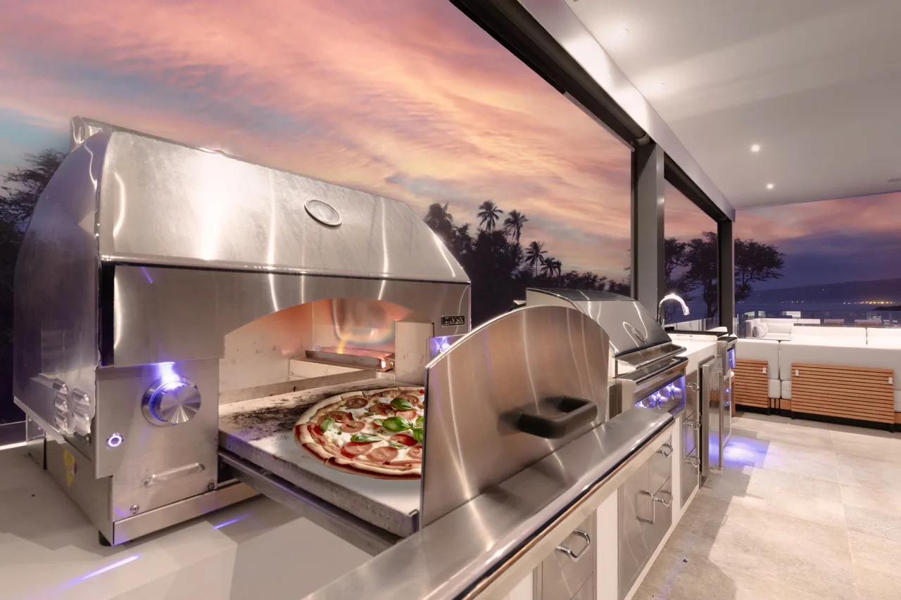 An outdoor kitchen with stainless steel cooking equipment and a view of the sunset.