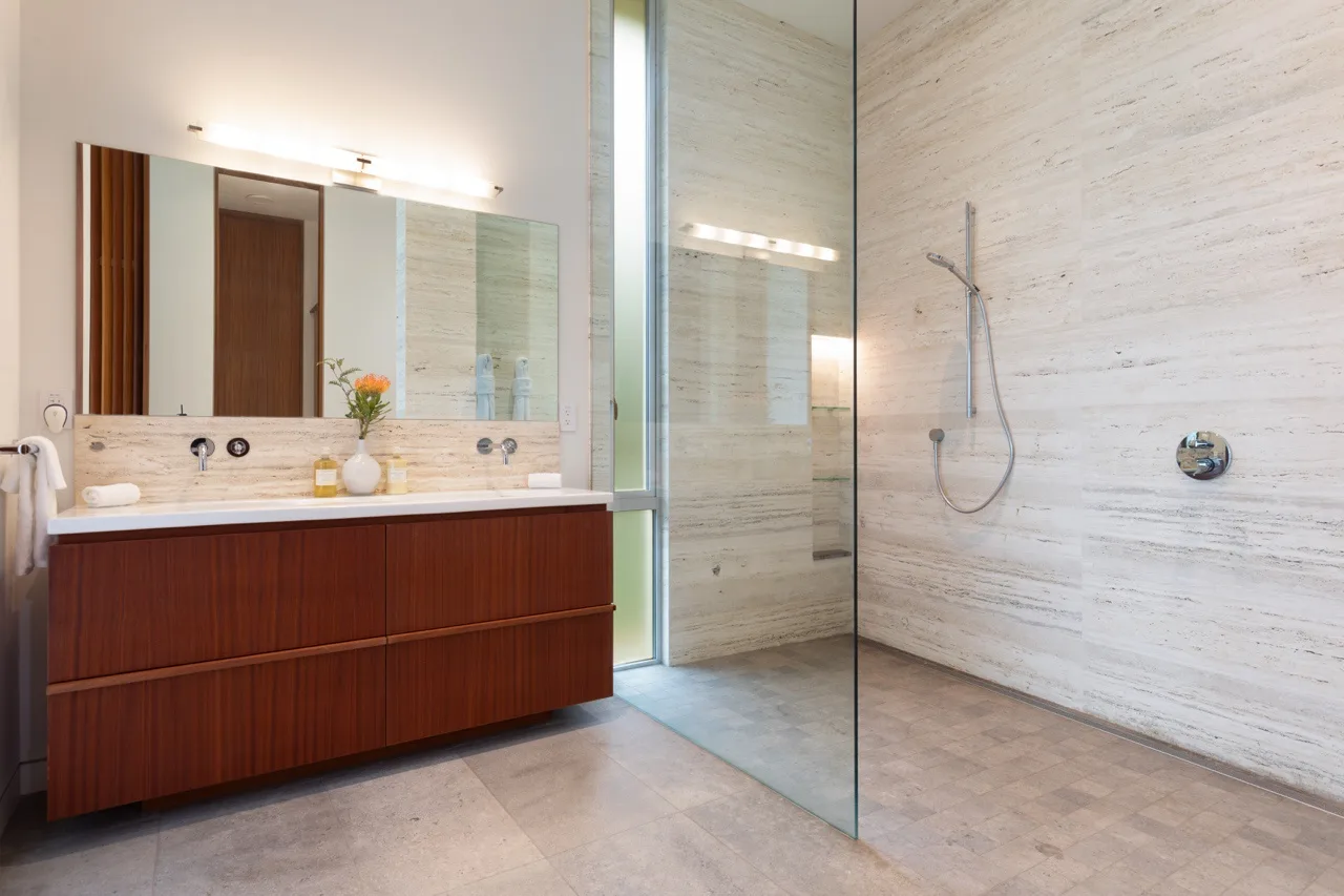 A bathroom with a long vanity and a glass-enclosed shower.