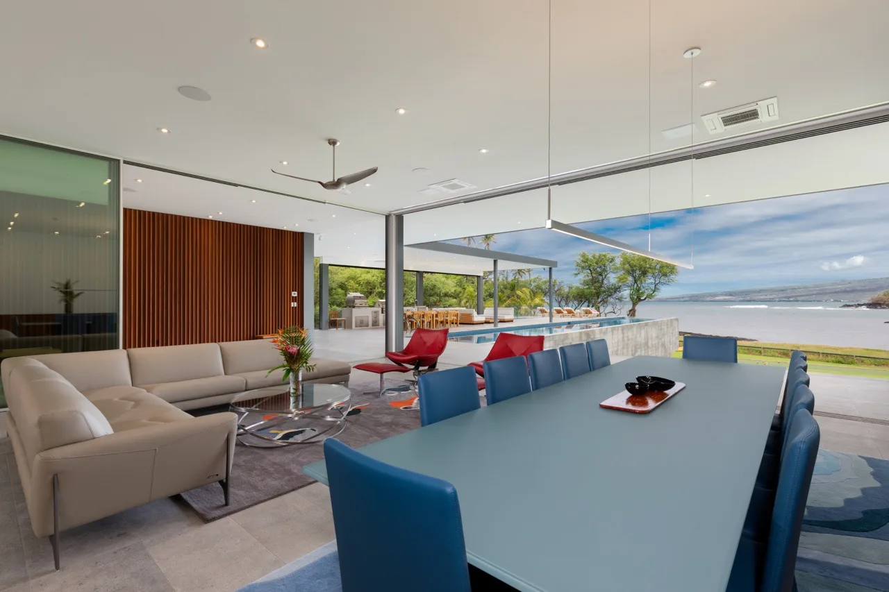A modern living and dining area opens onto a patio with a water view.