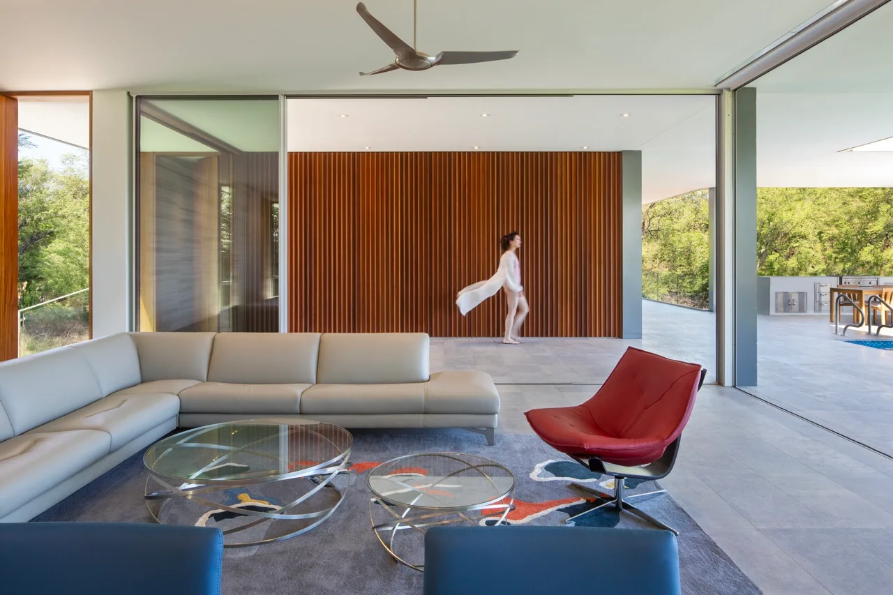 A modern living room opens onto a patio, with a large sectional and red accent chair.
