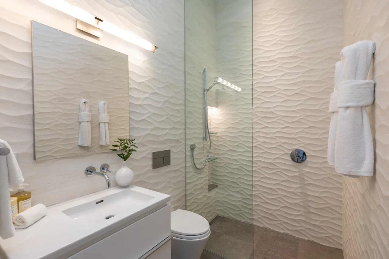 A bathroom with a sink, mirror, and glass shower.