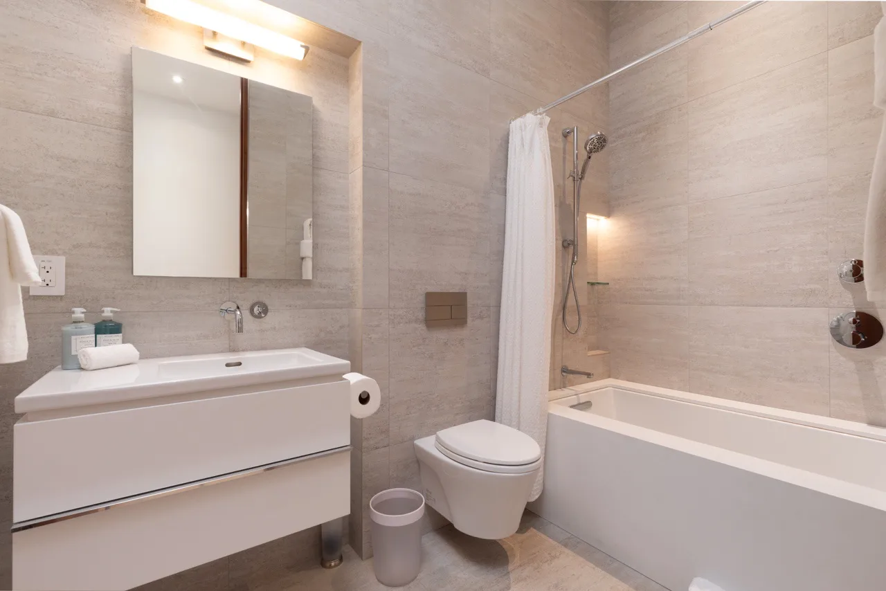 A bright bathroom with a sink, toilet, and bathtub behind a shower curtain.