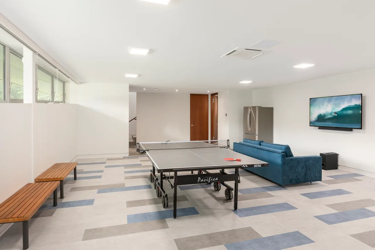 A recreation room with a ping-pong table, seating, and a wall-mounted television.