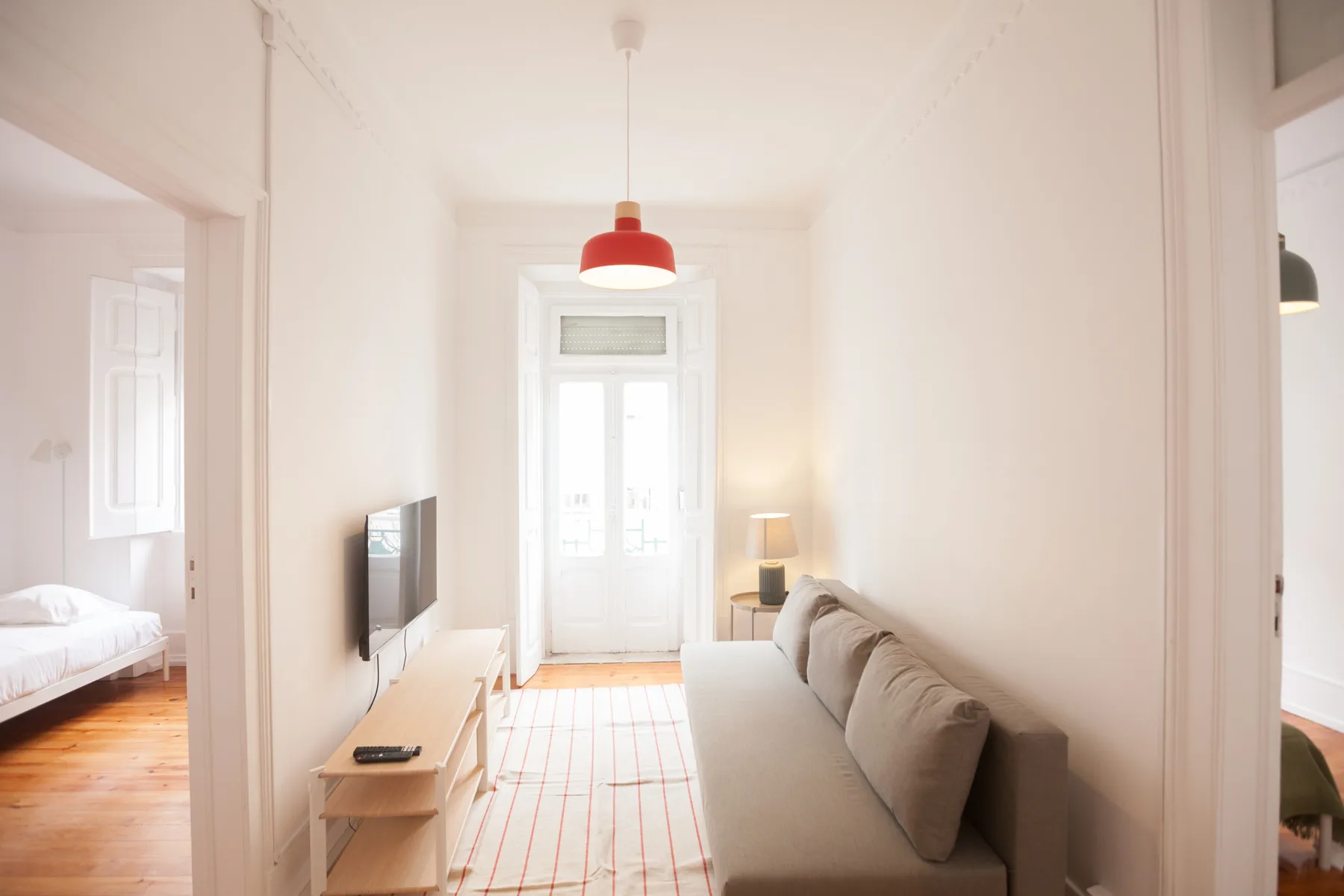 Una sala de estar luminosa con asientos, un televisor y una puerta acristalada.
