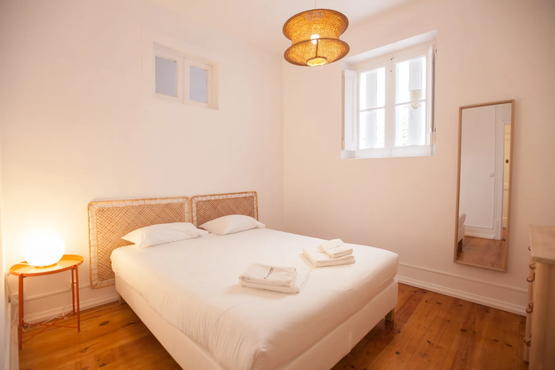 Dormitorio con cama doble, cabecero tejido y suelo de madera.