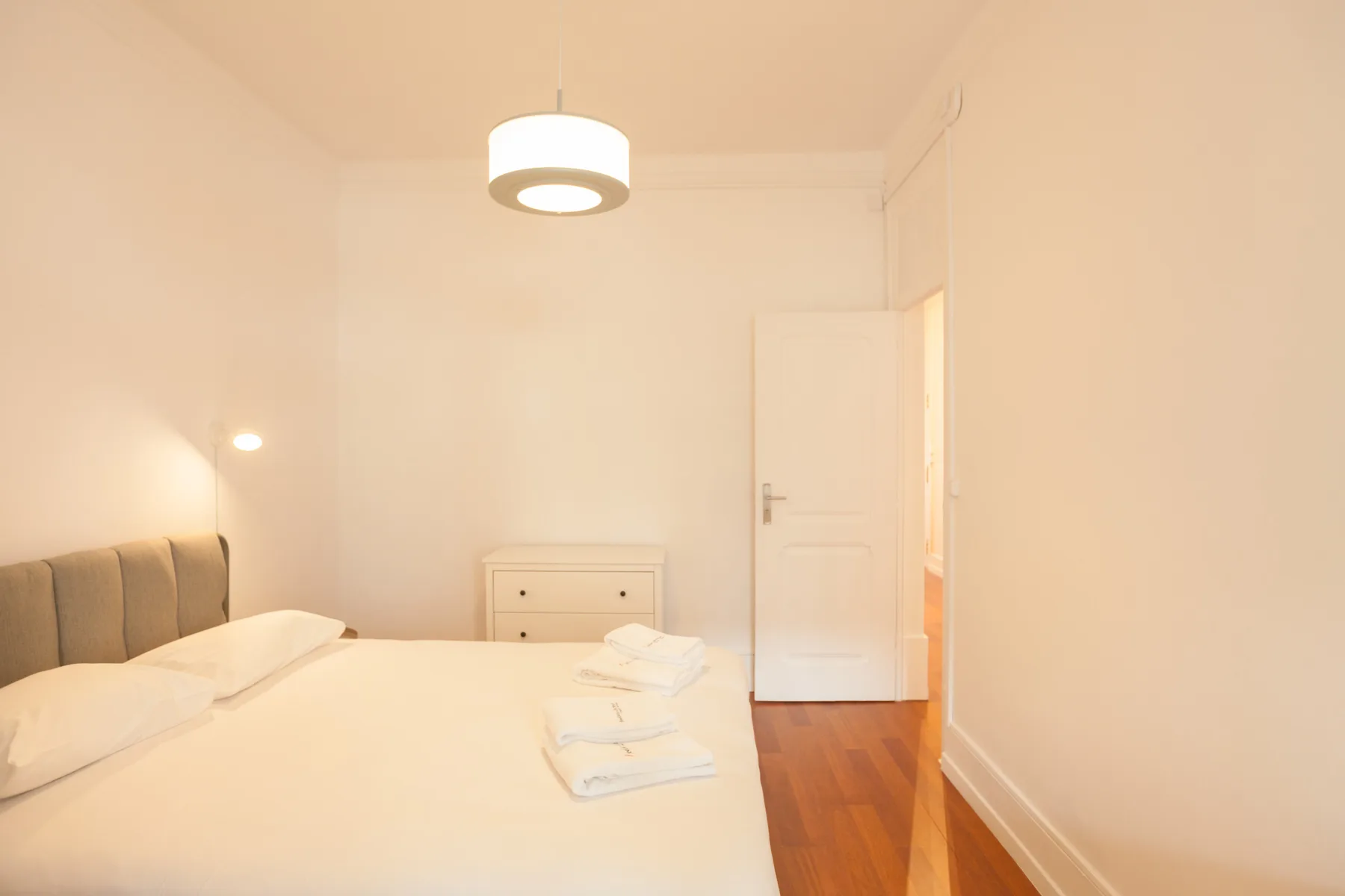 Dormitorio con una cama, toallas dobladas y una puerta.