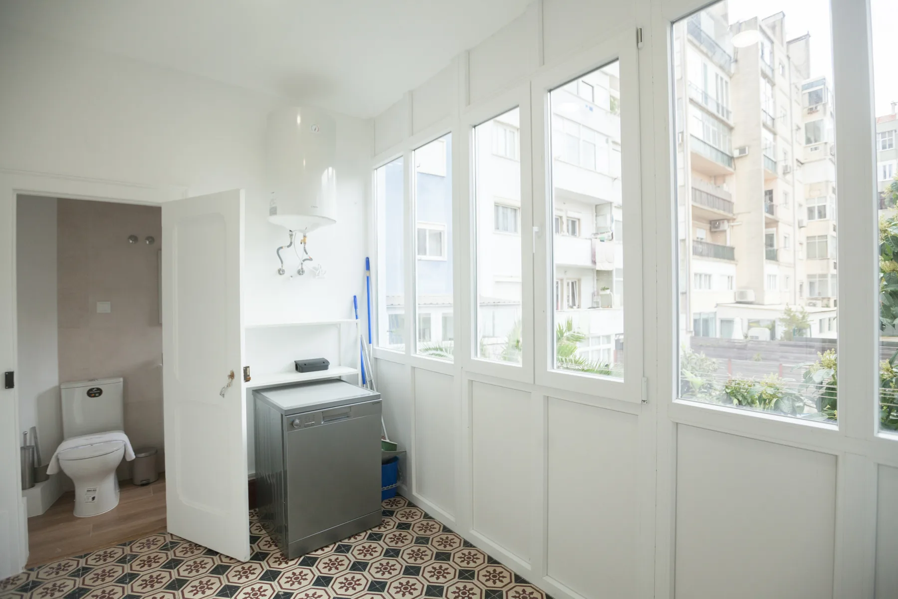 Un baño luminoso con inodoro, lavabo y ventanales.