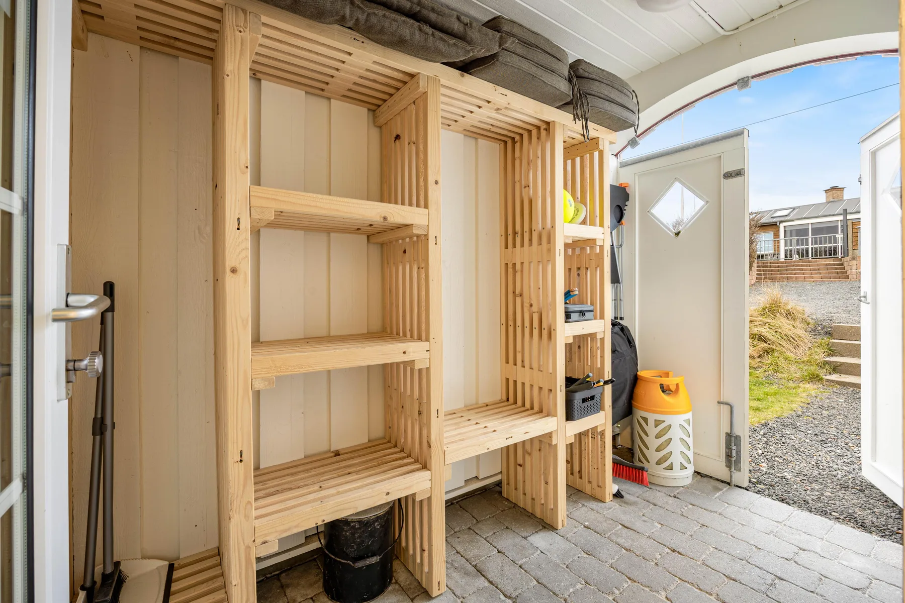 Una sala de sauna con bancos de madera y una puerta abierta al exterior.