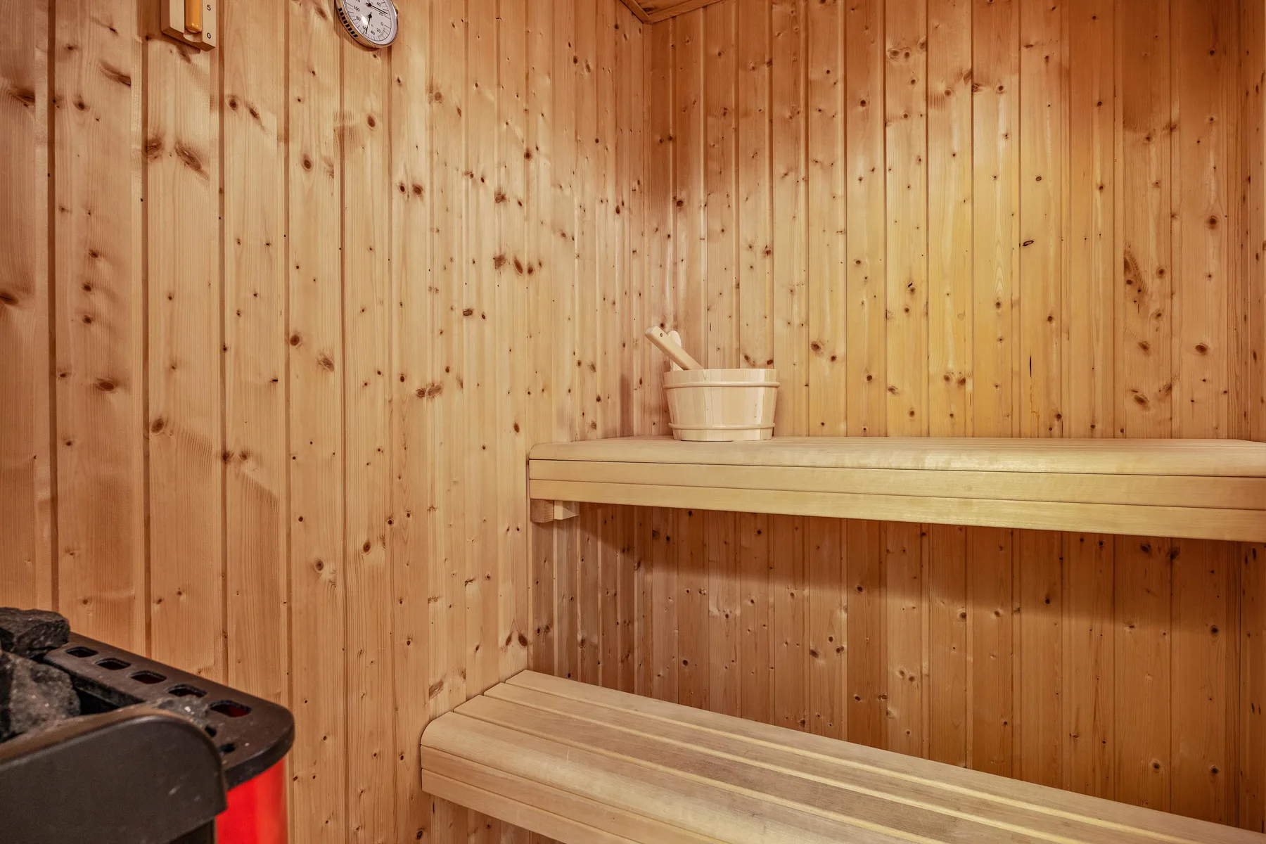 Una sauna revestida de madera con un calentador y asientos de madera escalonados.