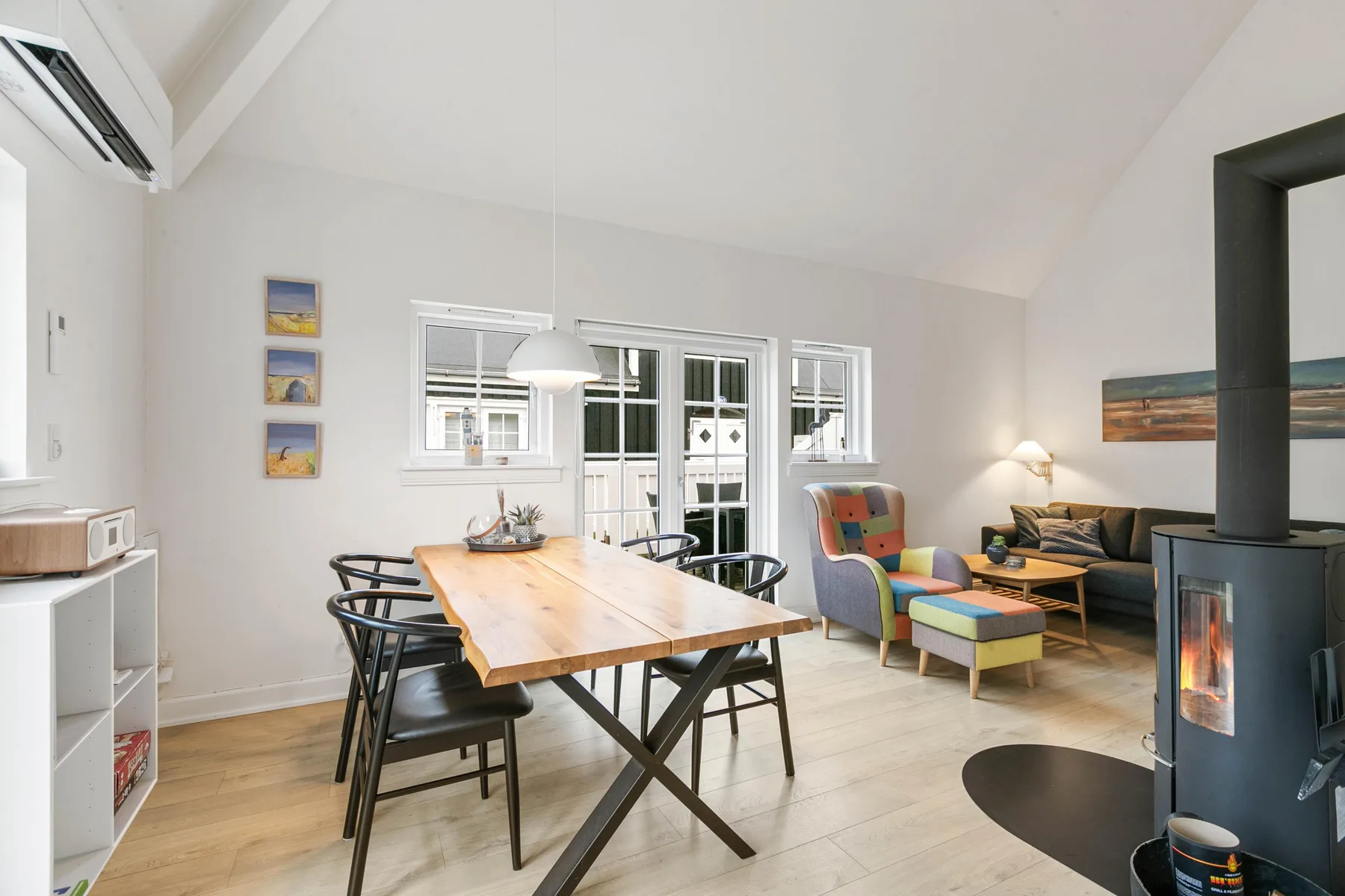 Una luminosa sala de estar y comedor con una mesa de madera, asientos y una estufa.